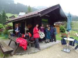 Anstatt einer gemütlichen Vesperpause auf einer Wiese müssen die Wanderer bei strömendem Regen an einem Kiosk unterstehen und genießen dort ihre Brotzeit - die Stimmung ist trotzdem gut! 
